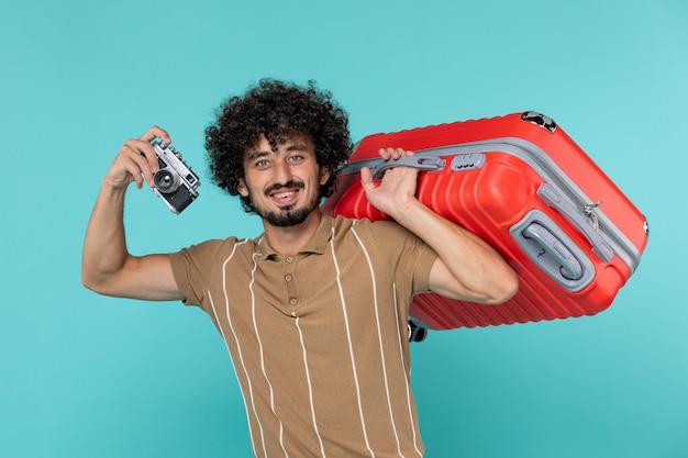 Free photo man in vacation with big suitcase taking photos with camera on blue