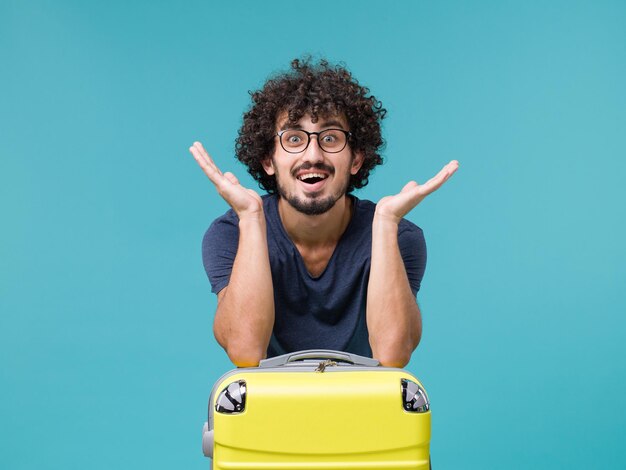 man in vacation with big yellow suitcase feeling happy on blue
