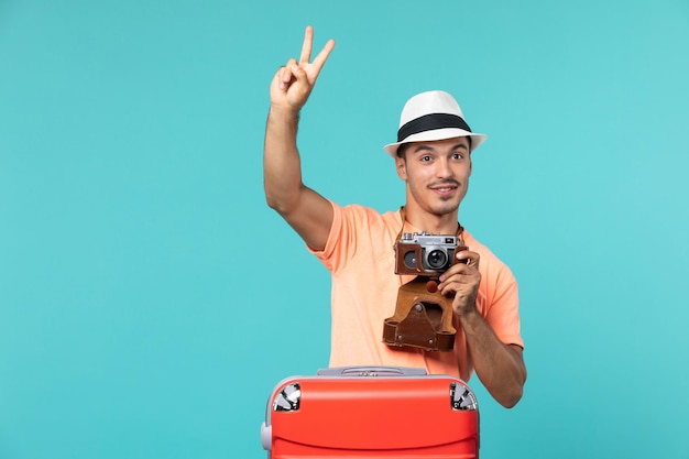человек в отпуске с красным чемоданом и фотоаппаратом на голубом