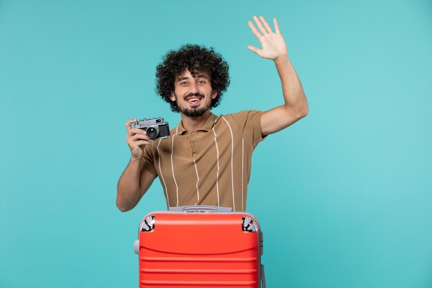 man in vacation with red suitcase taking photos with camera on blue