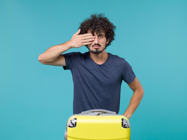 man in vacation with yellow suitcase on blue