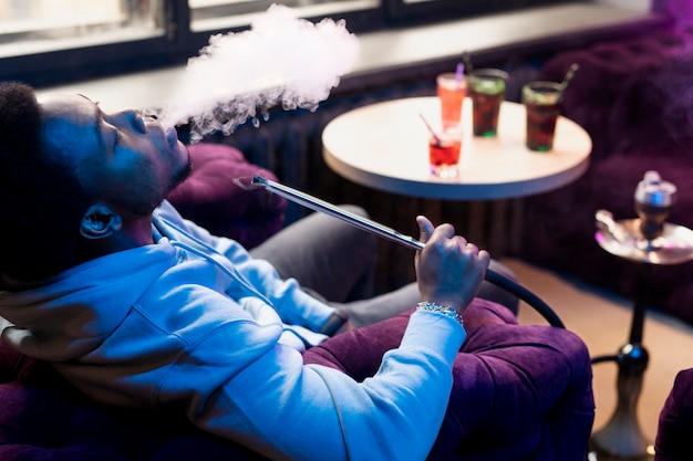 Man vaping from a hookah indoors