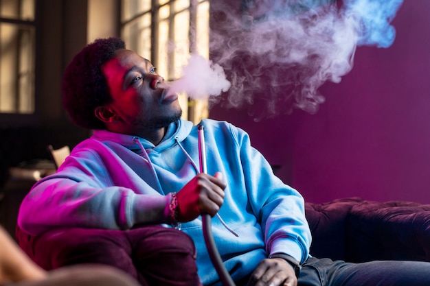 Free photo man vaping from a hookah indoors