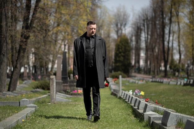 Мужчина посещает надгробие на кладбище