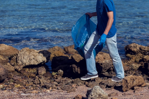 Человек-волонтер с большим мешком для сбора мусора на пляже. концепция загрязнения окружающей среды