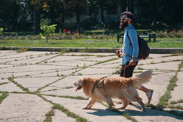 Человек гуляет со своей собакой в парке