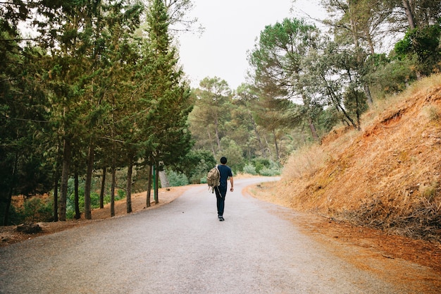 man walking on road in forest