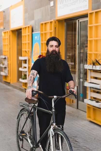 Foto gratuita uomo che cammina sulla strada tenendo la sua bicicletta