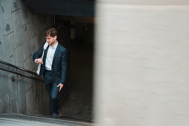 Man walking on subway staircase watching time