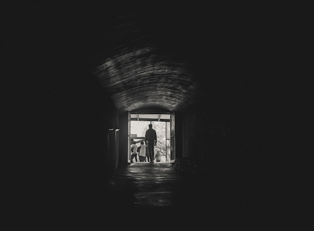トンネルの終わりに光の方へ歩いている男