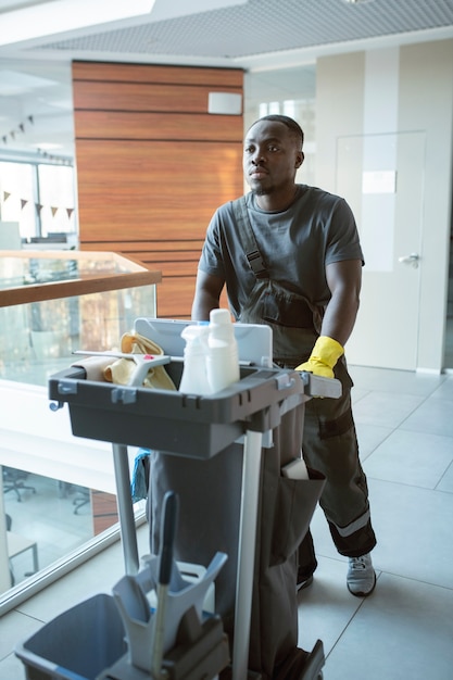 Free photo man walking with cleaning cart full shot