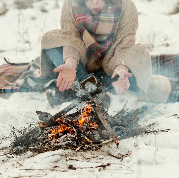 man warming up next to a campfire in winter