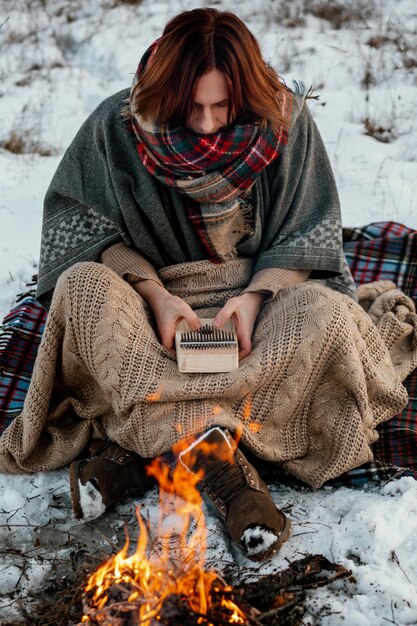 man warming up next to a campfire in winter