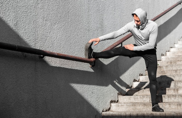 Man warming up his legs using a railing