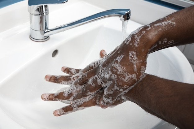 무료 사진 화장실에서 신중하게 손을 씻는 사람을 닫습니다. 감염 및 독감 바이러스 확산 예방