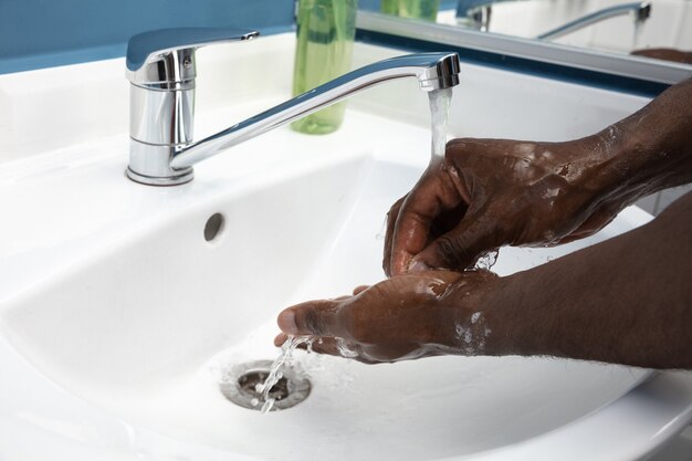 Man washing hands carefully with soap and sanitizer, close up.