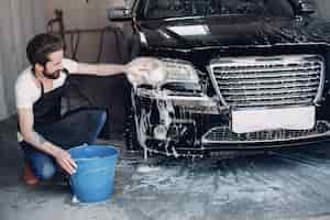 Free photo man washing his car in a garage