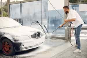 Free photo man washing his car in a washing station