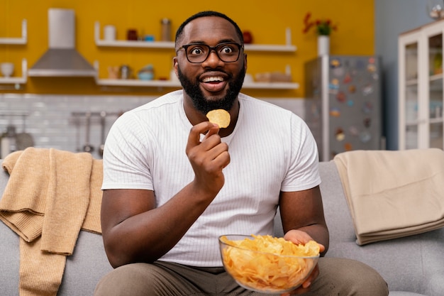 テレビを見たり、チップを食べたりする男