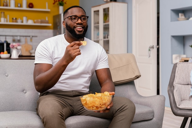 テレビを見たり、チップを食べたりする男