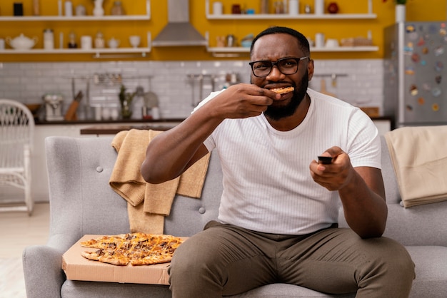 テレビを見てピザを食べる男