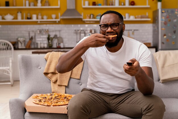 Человек смотрит телевизор и ест пиццу