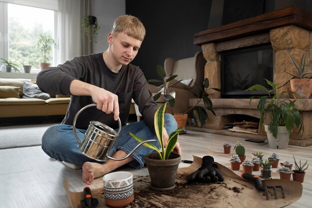 Man watering plant at home full shot