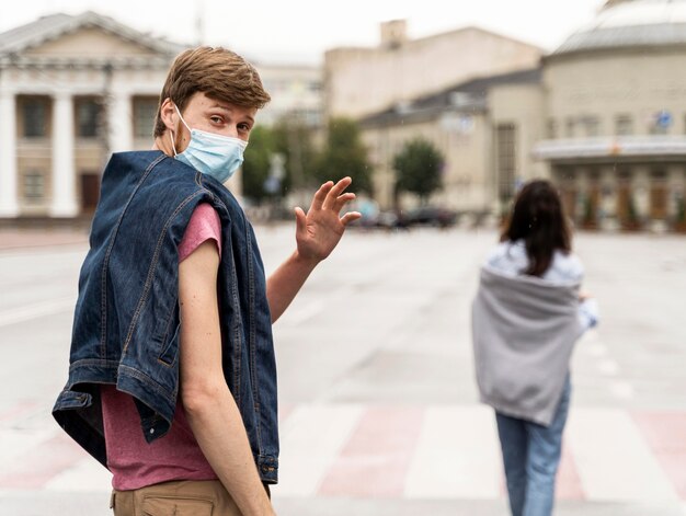 Man waving while wearing a medical mask