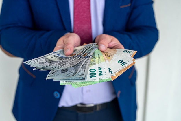 Man wear blue suit holding euro and dollars bills. investment concept Premium Photo