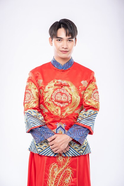 남자는 중국 새해에 여행자 쇼핑을 환영하기 위해 Cheongsam 미소를 입는다.