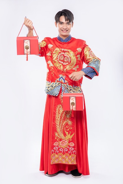 L'uomo indossa un abito cheongsam e una scarpa nera felice di ricevere una borsa rossa per sorprendere nel capodanno cinese