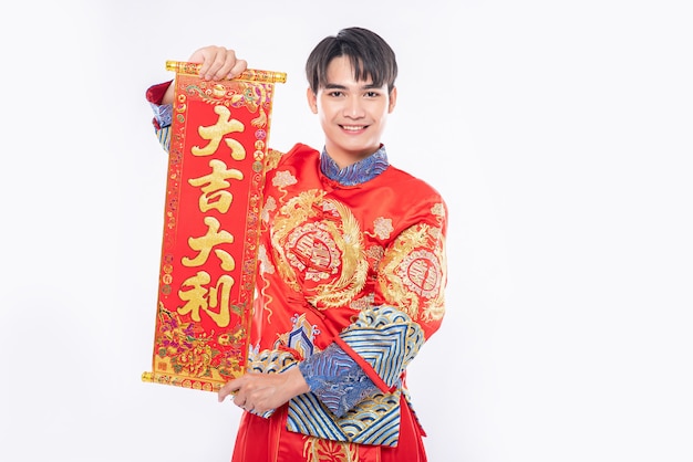 男はチャイナドレスのスーツを着て、家族に中国の旧正月の幸運のために中国のグリーティングカードを与える