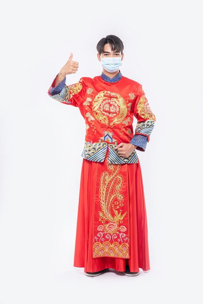 Мужчина в костюме и маске Cheongsam показывает лучший способ делать покупки для защиты от болезней