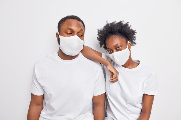 Человек носит одноразовые защитные маски от коронавируса, стоит близко друг к другу, не держит социальную дистанцию, одетый в повседневную белую футболку.