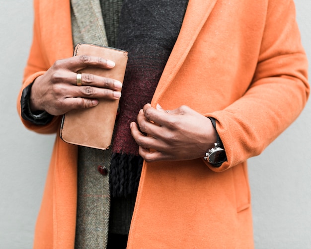Мужчина в оранжевом пальто держит свой кошелек
