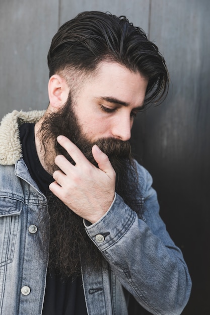 Foto gratuita uomo che indossa giacca di jeans in piedi contro la superficie del nero