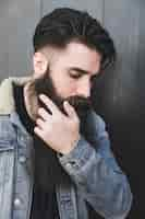 Free photo man wearing denim jacket standing against black surface