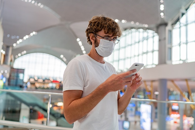 Man wearing face protective medical mask using smartphone