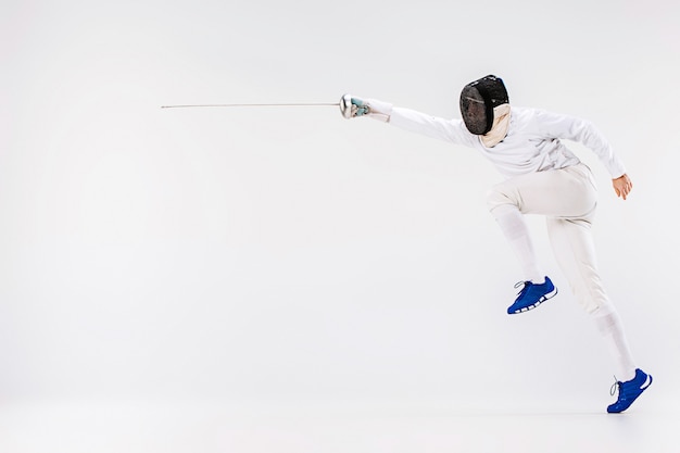 Free photo man wearing fencing suit practicing with sword against gray