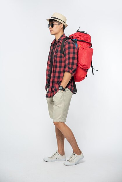 A man wearing glasses goes out to travel, wear a hat and carry a backpack