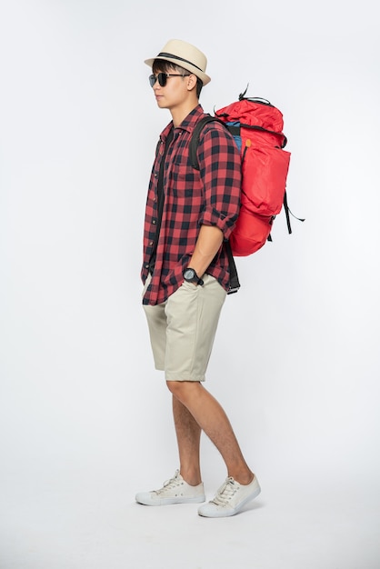 A man wearing glasses goes out to travel, wear a hat and carry a backpack