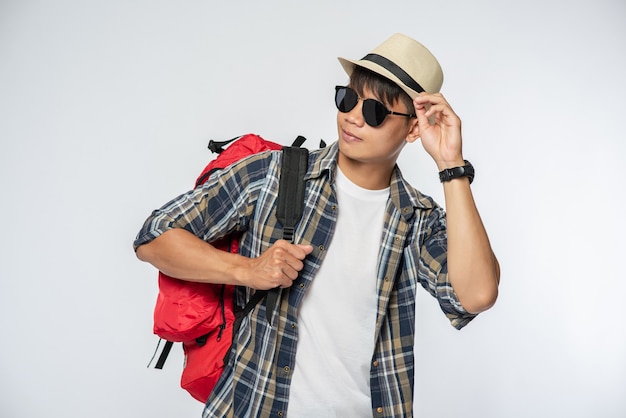 Мужчина в очках отправляется в путешествие, носит шляпу и несет рюкзак