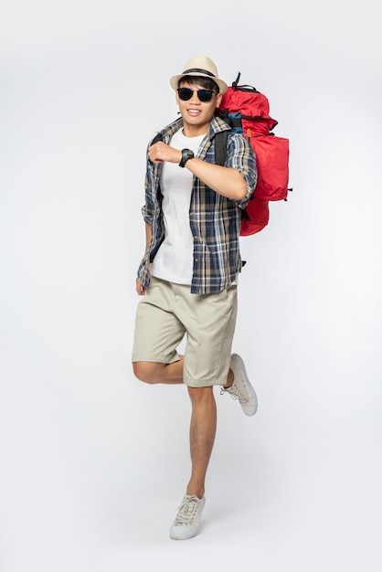 A man wearing glasses goes out to travel, wear a hat and carry a backpack