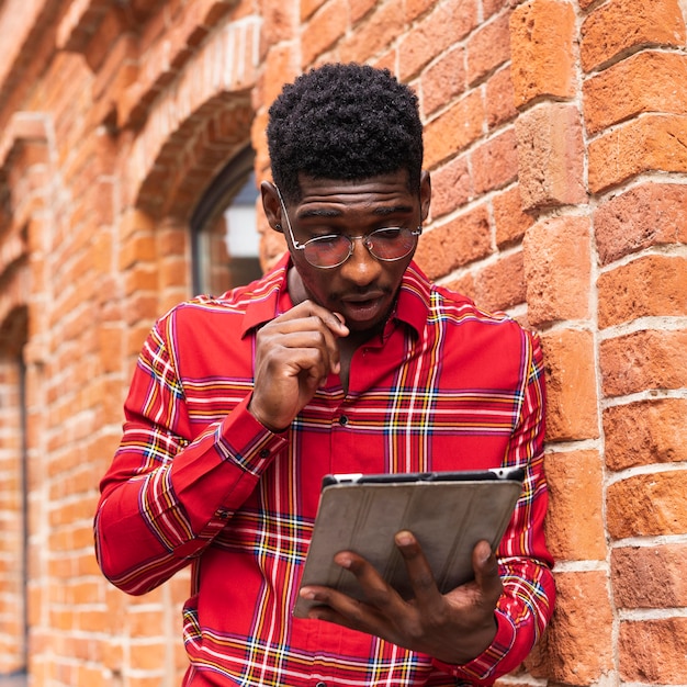 Free photo man wearing glasses and reading from his digital tablet