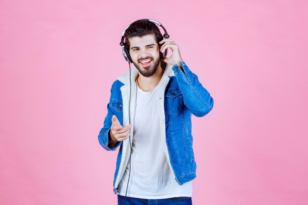 Man wearing headphones pointing to the someone on the right