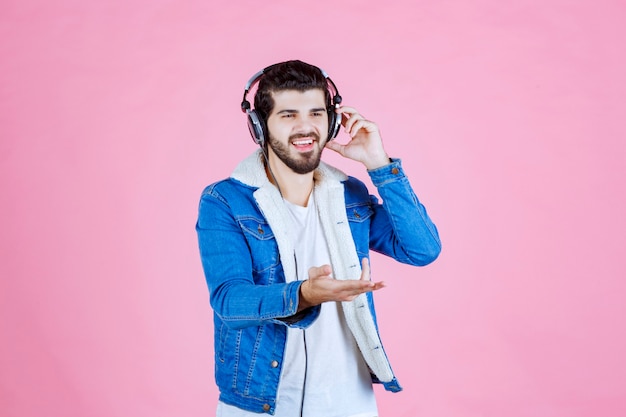 Man wearing headphones pointing to the someone on the right