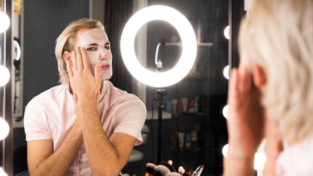 Man wearing make-up applying a facial mask