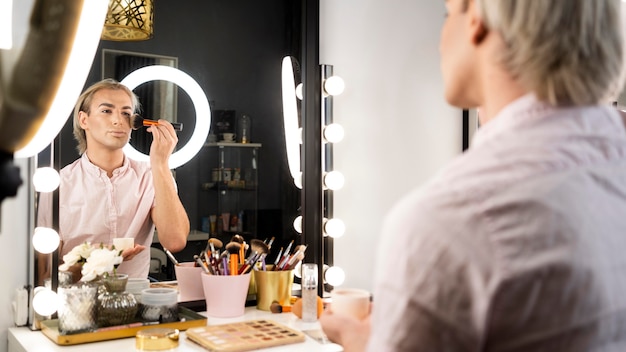 Man wearing make-up sing a brush on his face