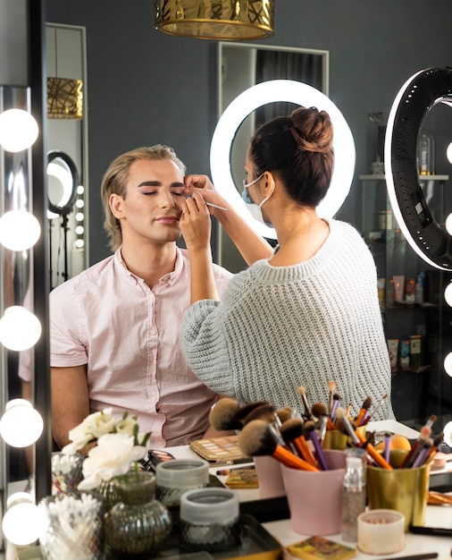 Foto gratuita uomo che indossa il trucco e donna che lo aiuta