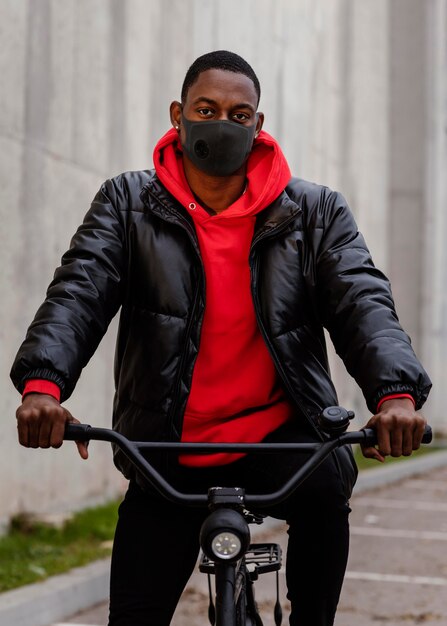 マスクを着用し、自転車を持っている男